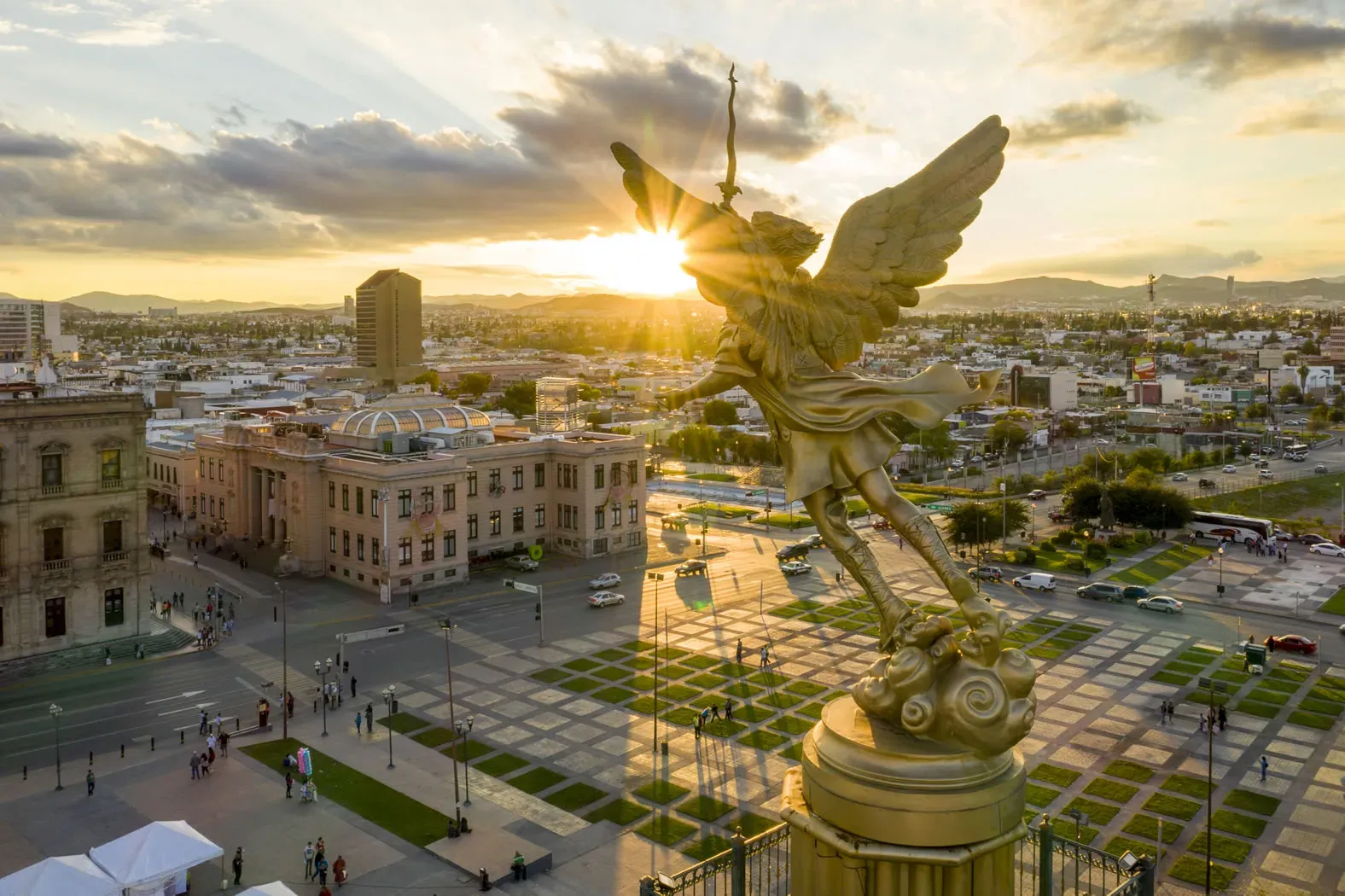 Ángel dorado sobre la ciudad de Chihuahua al atardecer vista aérea