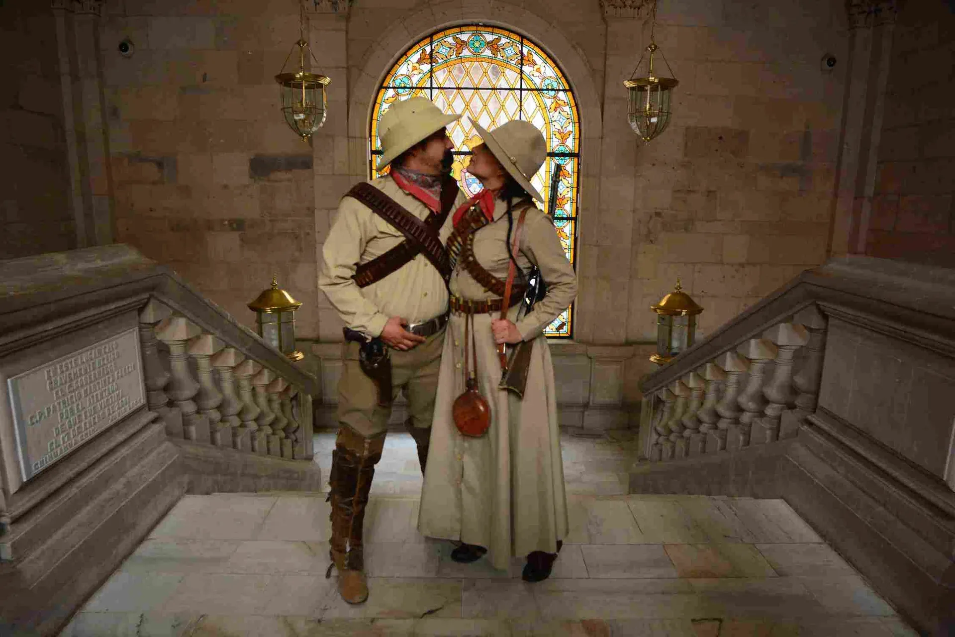 Pareja disfrazada de revolucionarios mexicanos en escalinata del Palacio de Gobierno
