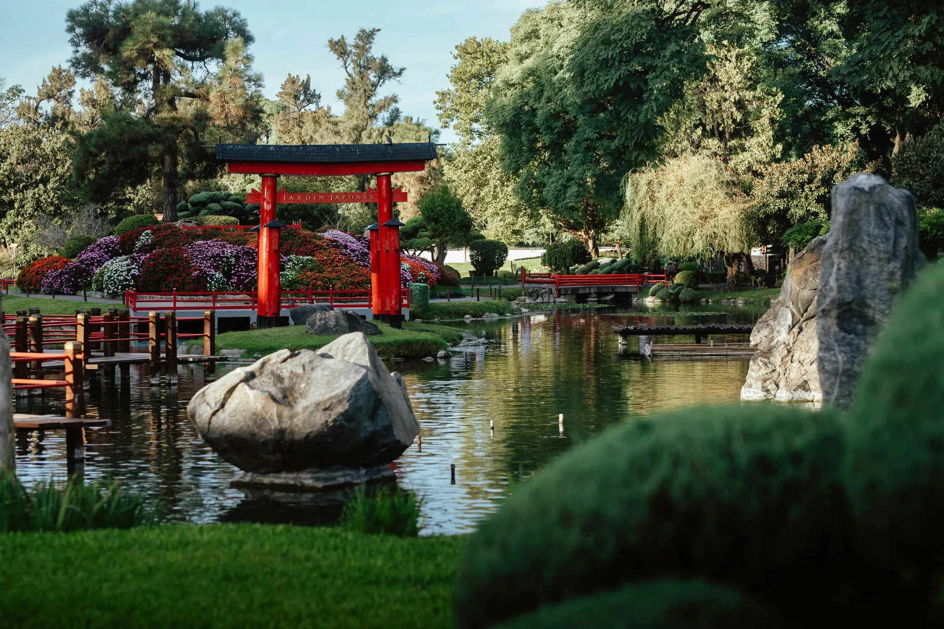 Jardín japonés con torii rojo, estanque, rocas y vegetación cuidada al estilo japonés