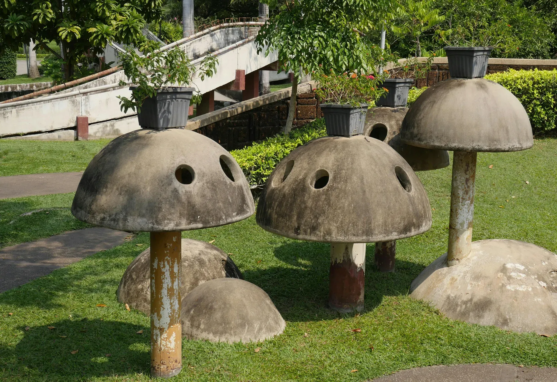 Esculturas de hormigón con forma de hongos surrealistas en un jardín tropical