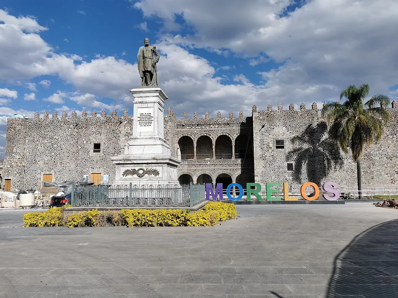 Palacio de Cortés con letras MORELOS coloridas y cielo nublado