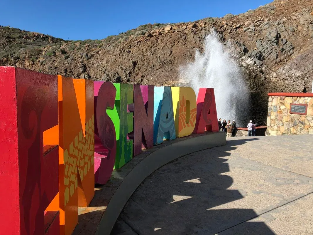 Cartel de Ensenada con olas rompiendo contra rocas en la costa de Baja California