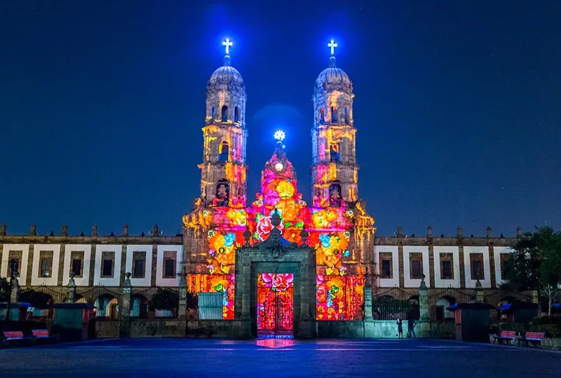 Basilica de Zapopan iluminada con mapping de luz multicolor de noche