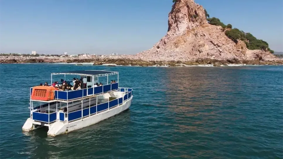 Lancha con pasajeros navegando hacia la formación rocosa de Isla de la Piedra