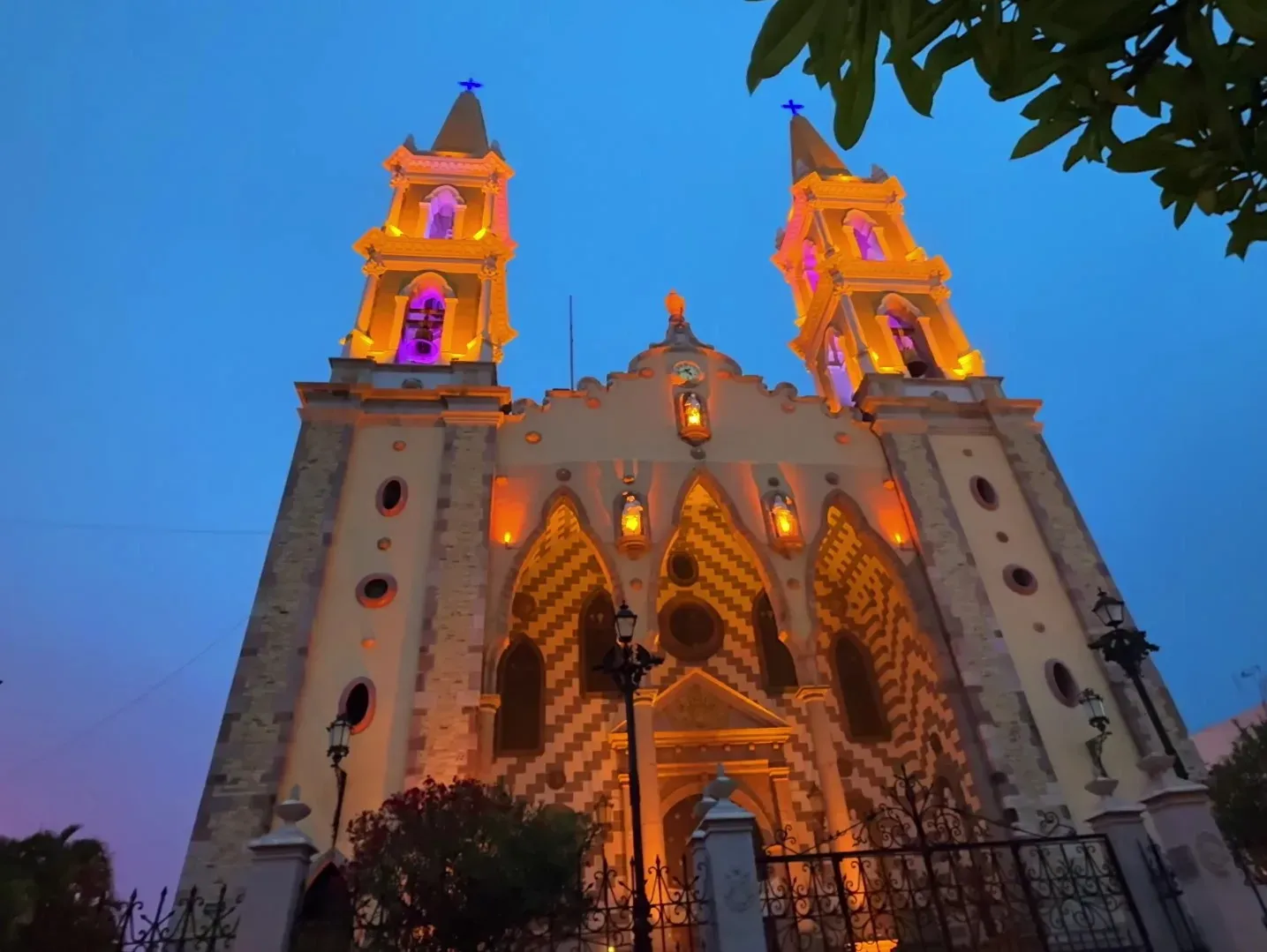 Fachada de la Catedral de la Inmaculada Concepción iluminada de noche con luces doradas y moradas