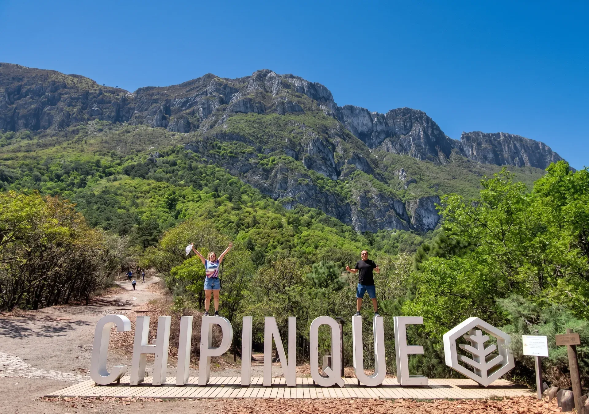 Senderistas posando junto a las letras de Chipinque con la Sierra Madre Oriental de fondo