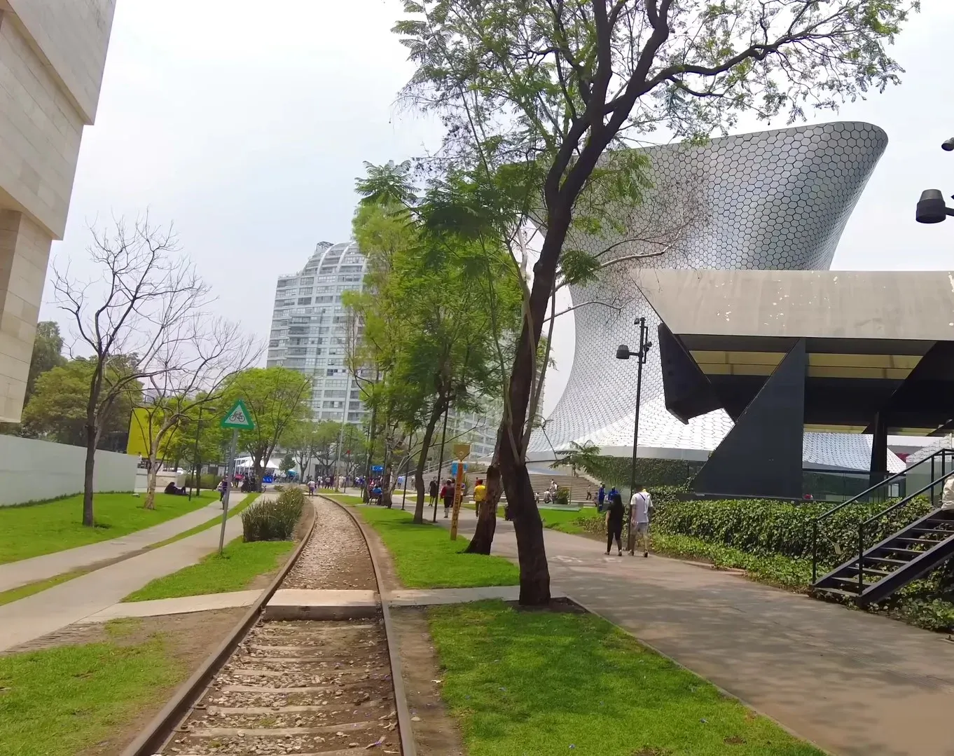 Plaza Carso con el Museo Soumaya al fondo, andador con vías y visitantes paseando