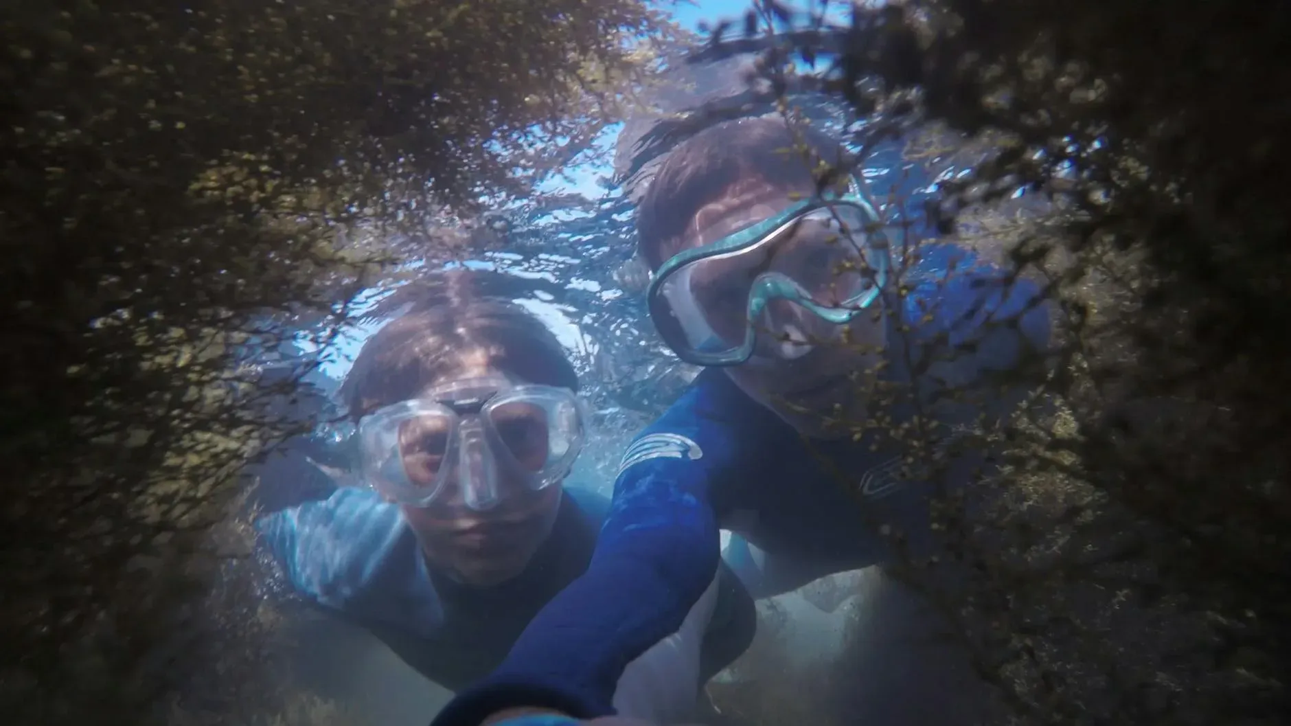 Pareja en snorkel en cueva marina con arrecife