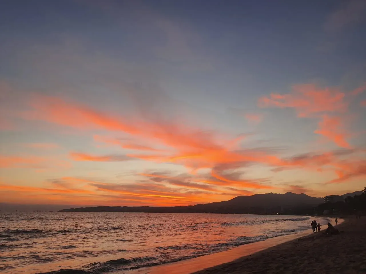 Atardecer en la playa de Punta de Mita con cielo naranja y montanas al fondo
