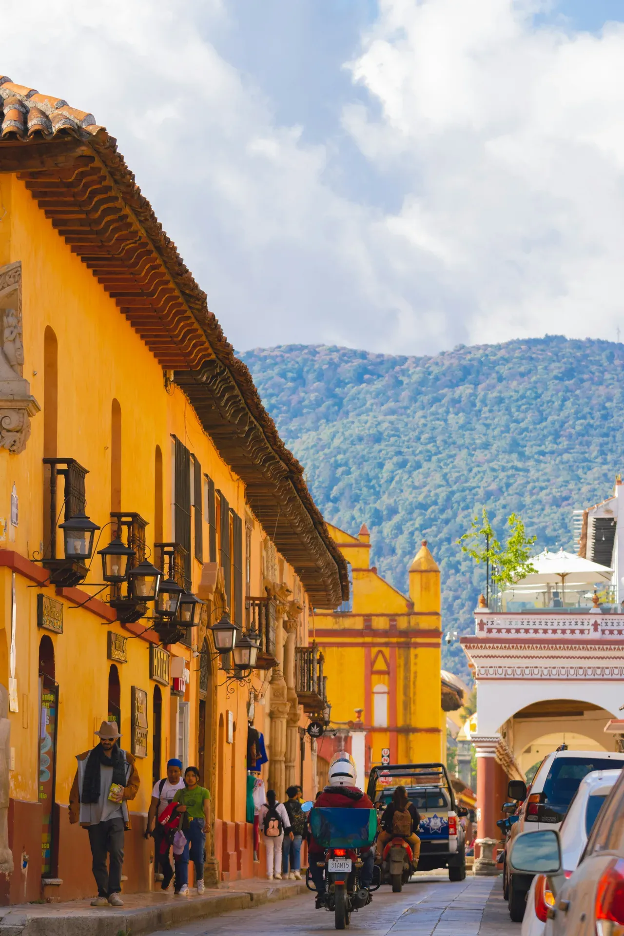 Calle colonial de colores amarillos con montanas al fondo en San Cristobal