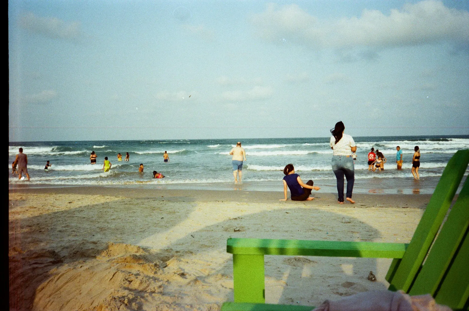 Playa con bañistas y silla de playa verde en la costa del Golfo de México