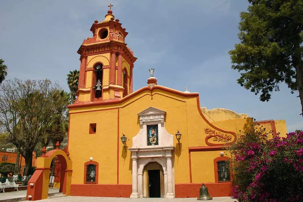 Templo de San Sebastián Mártir con fachada amarilla y torre barroca en Bernal