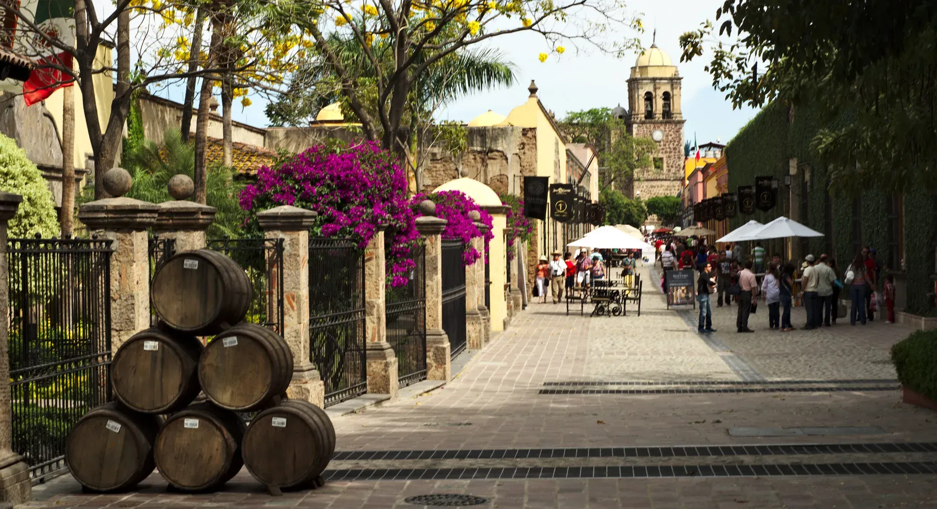 Calle empedrada del centro de Tequila con barricas y la parroquia