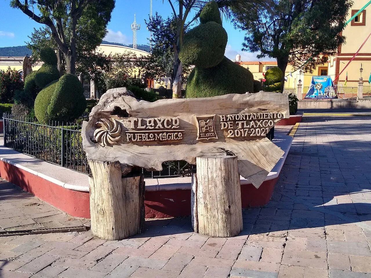Plaza principal de Tlaxco con letrero Pueblo Mágico y topiary