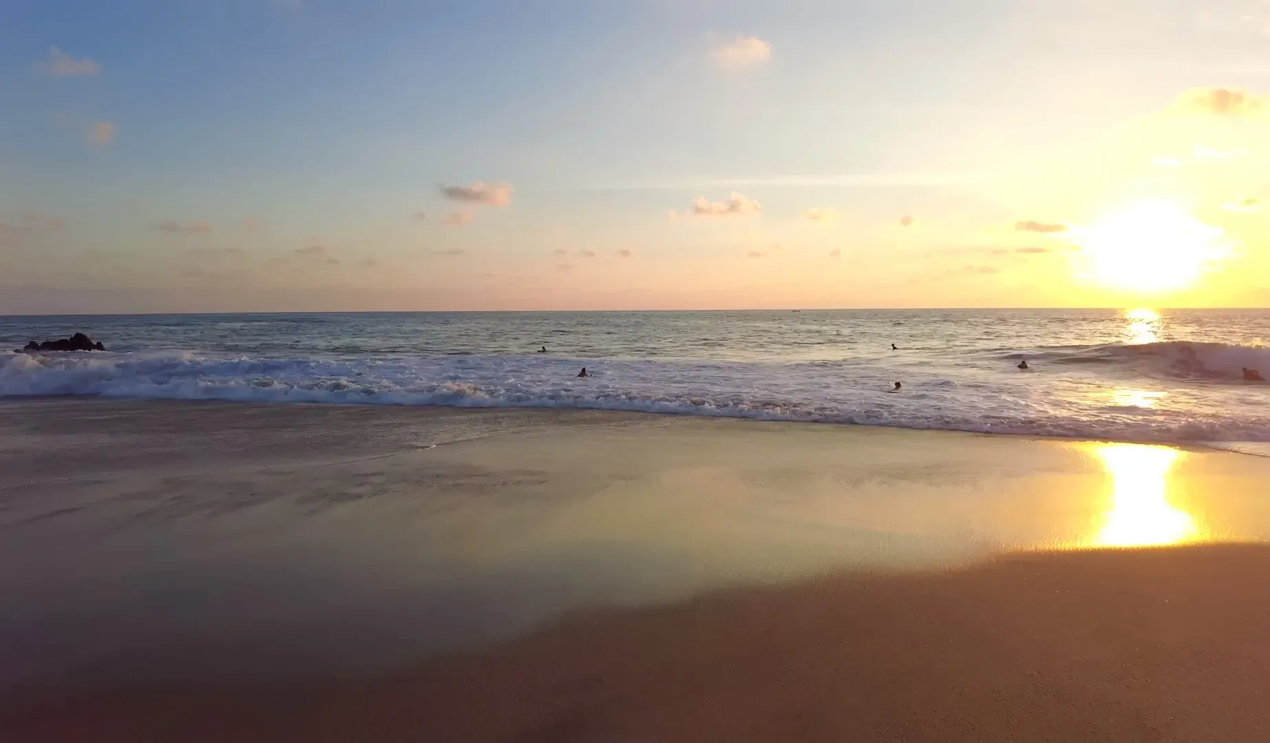 Atardecer dorado en Playa Zicatela con surfistas en el agua